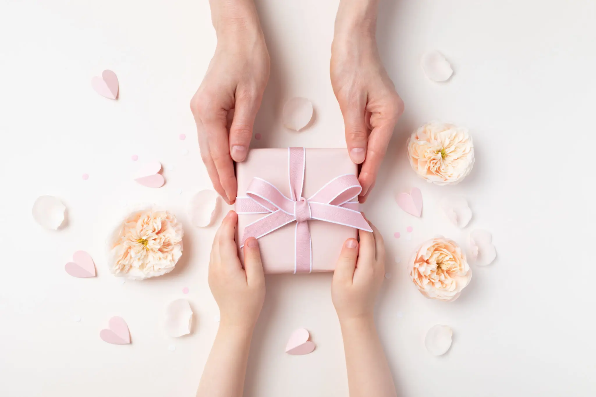Hands exchanging pink gift with flowers.