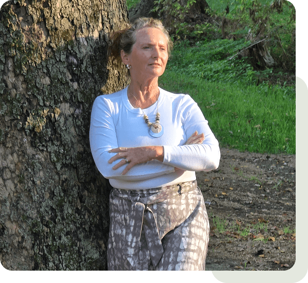Woman leaning against tree in sunlight.