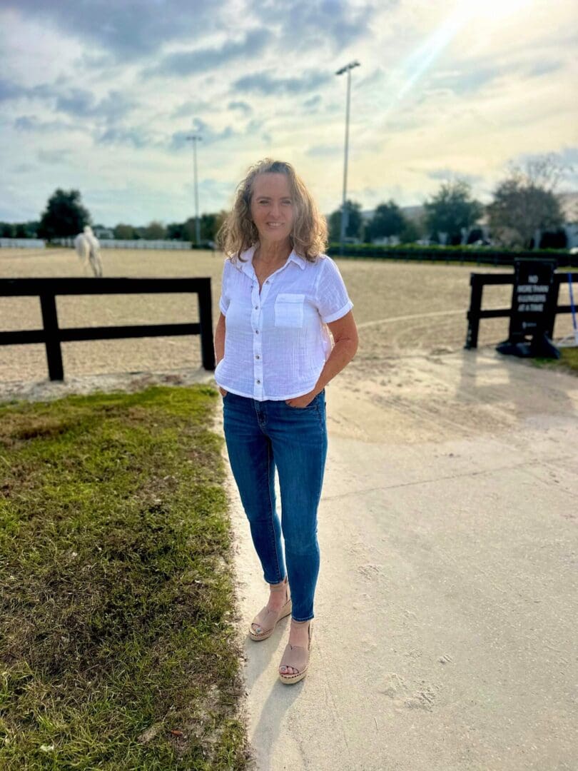 Woman standing near horse riding arena.